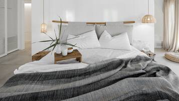 Un dormitorio moderno con una cama grande, mesitas de noche, una lámpara colgante y una planta en maceta.