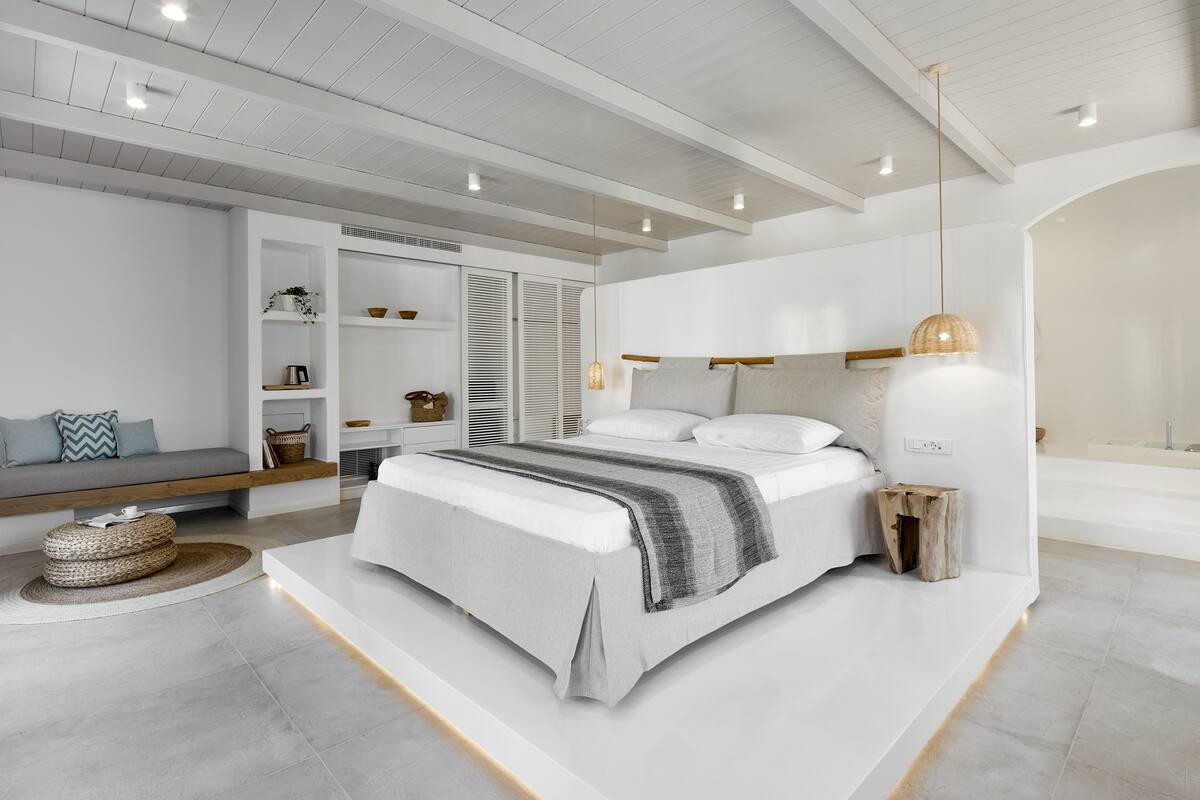 A modern bedroom with a large bed, built-in shelving, and a minimalist design.