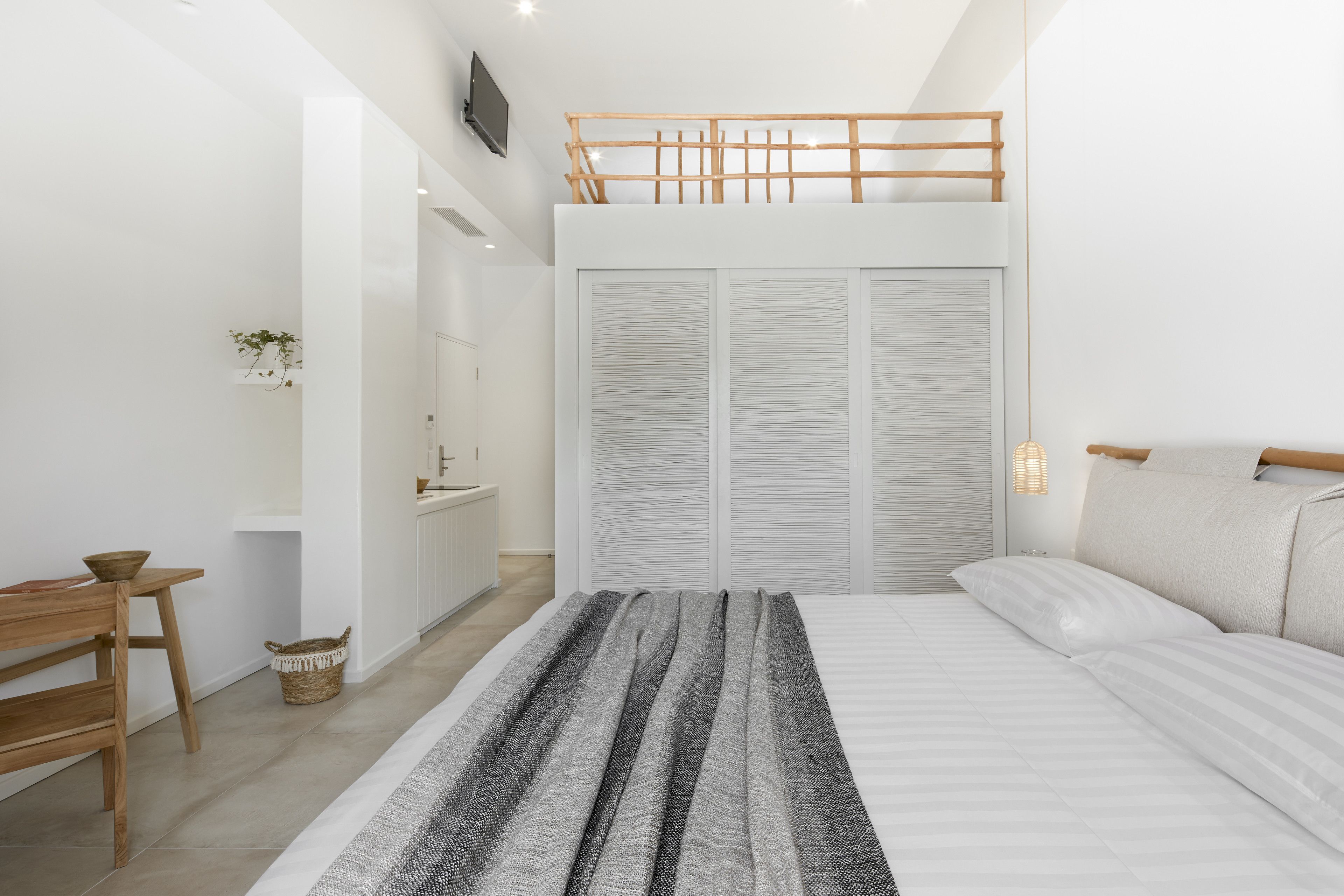 A bedroom with a bunk bed, a bedside table, a chair, a bedside lamp, and a large window.