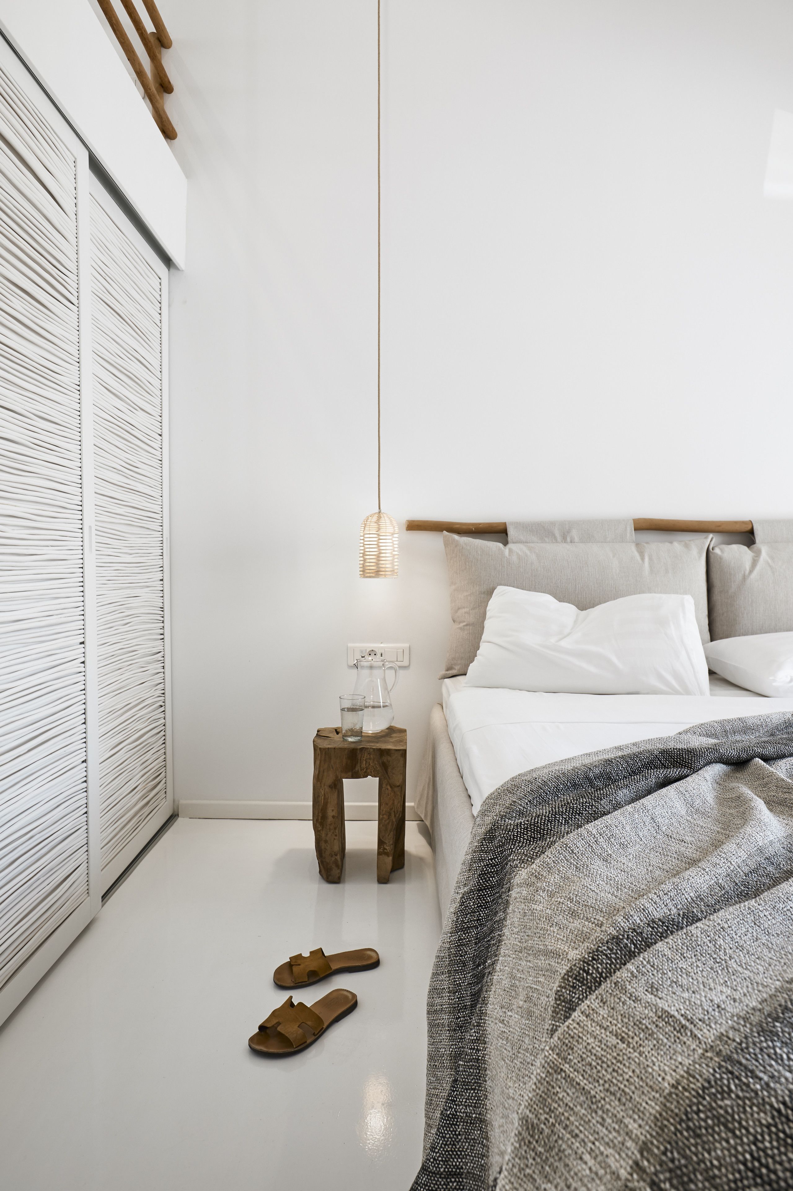 Une chambre à coucher avec un lit, une table de chevet et un luminaire suspendu.