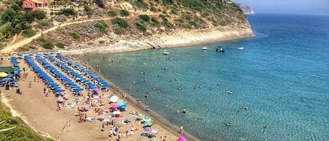 Nära stranden, solstolar, parasoller och volleyboll