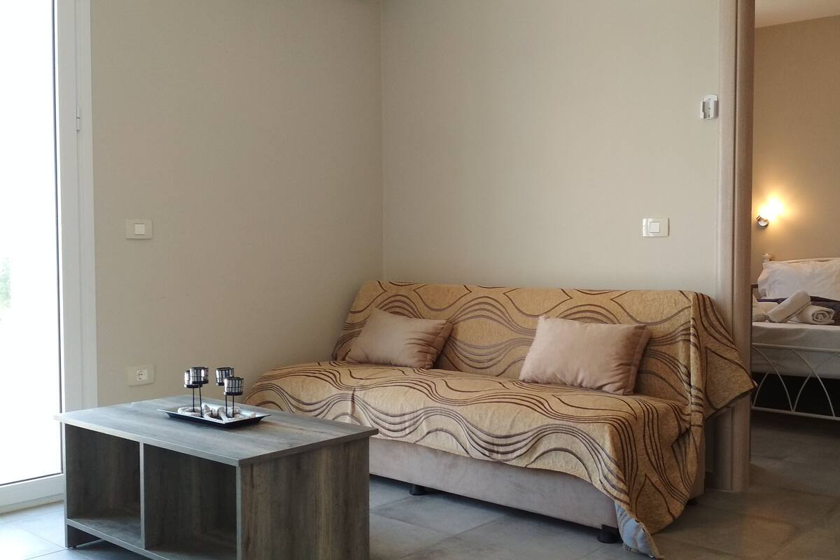 A corner room with a sofa, a small table, and a bed.
