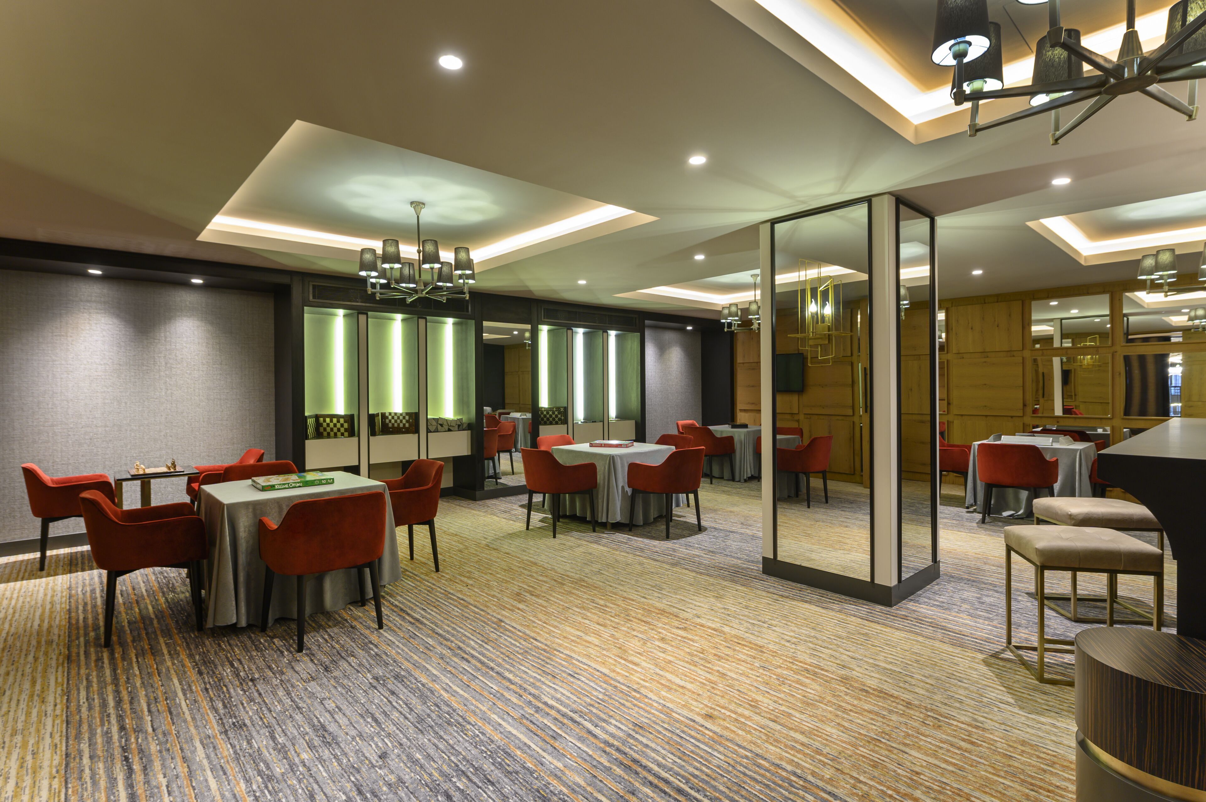 Un comedor de hotel con varias mesas y sillas, un candelabro y suelo alfombrado.