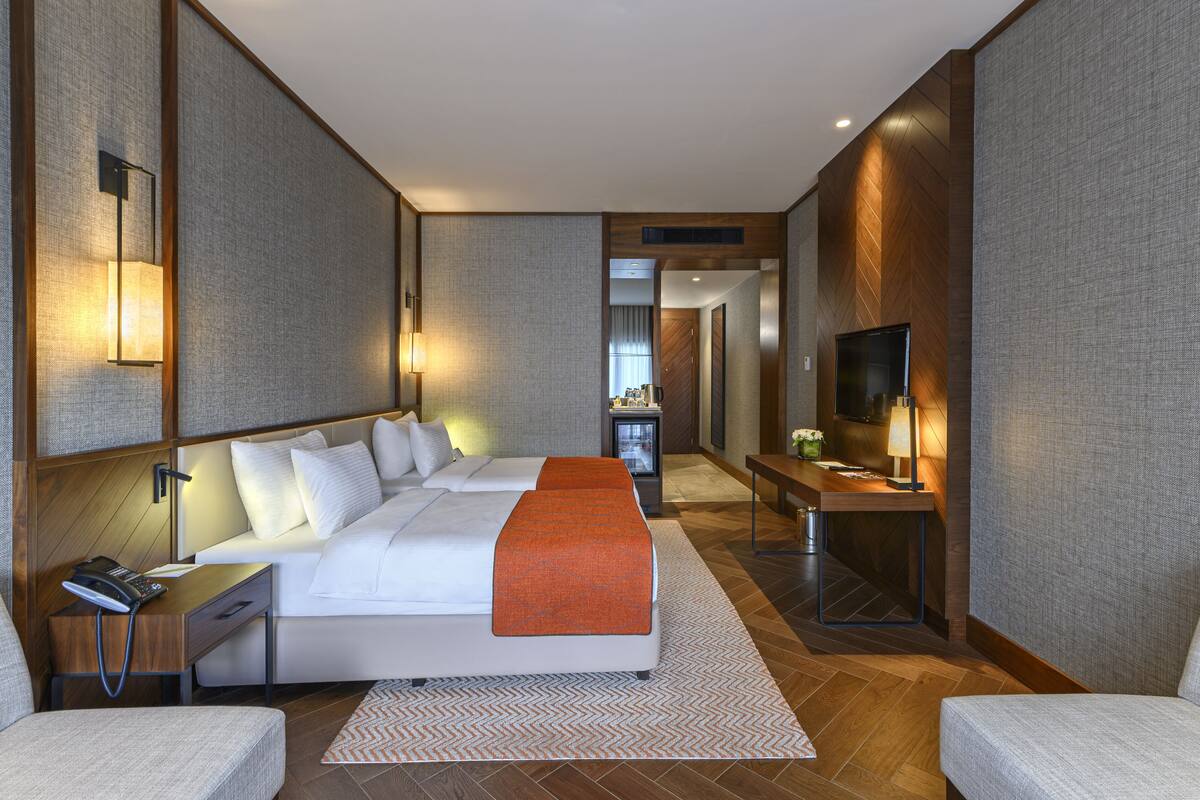 Een moderne hotelkamer met een groot bed, nachtkastjes, een bureau en een televisie.