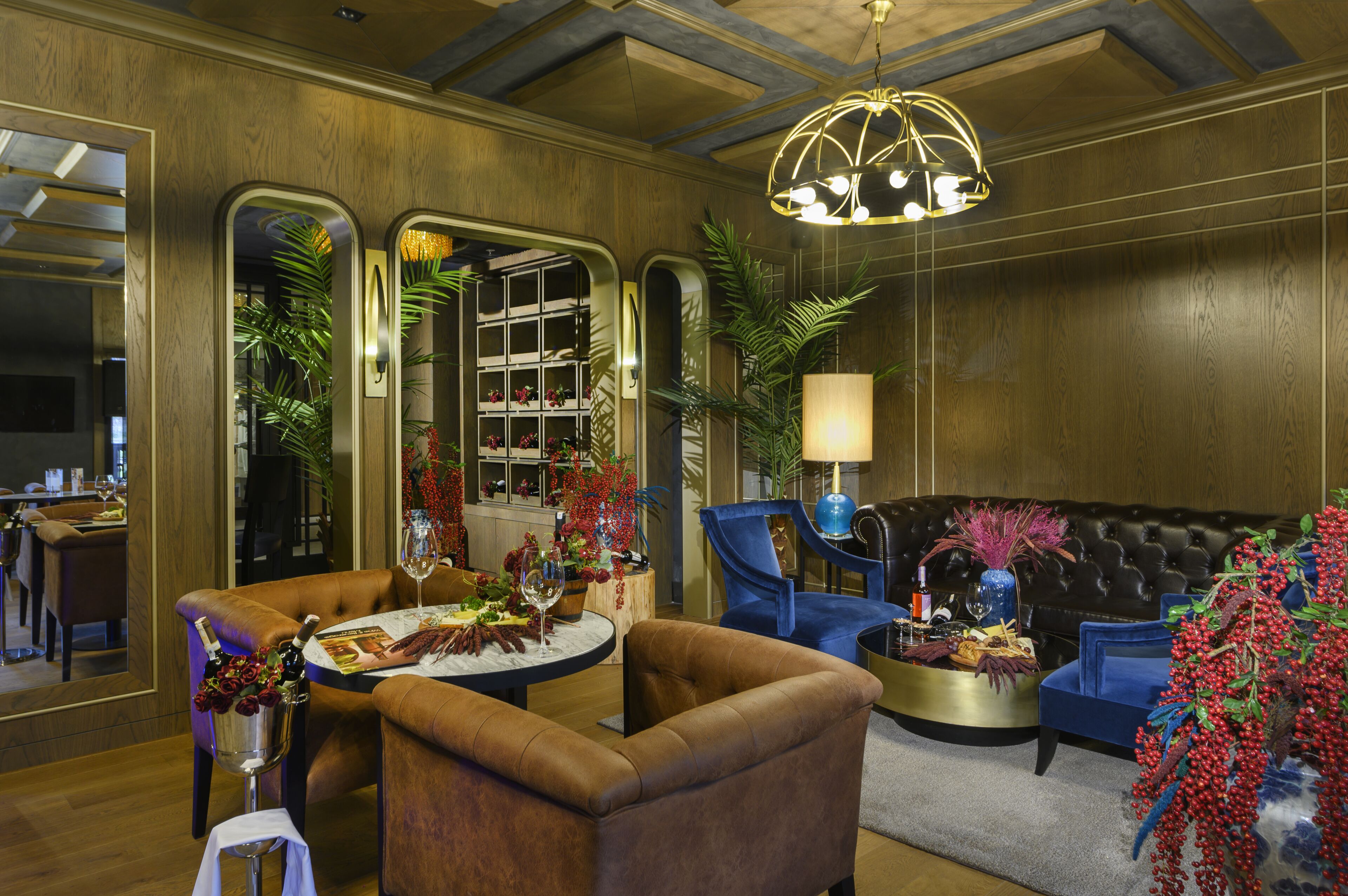 A luxurious room with a leather sofa, a round table with a bottle of champagne, and a large mirror reflecting the room's decor.
