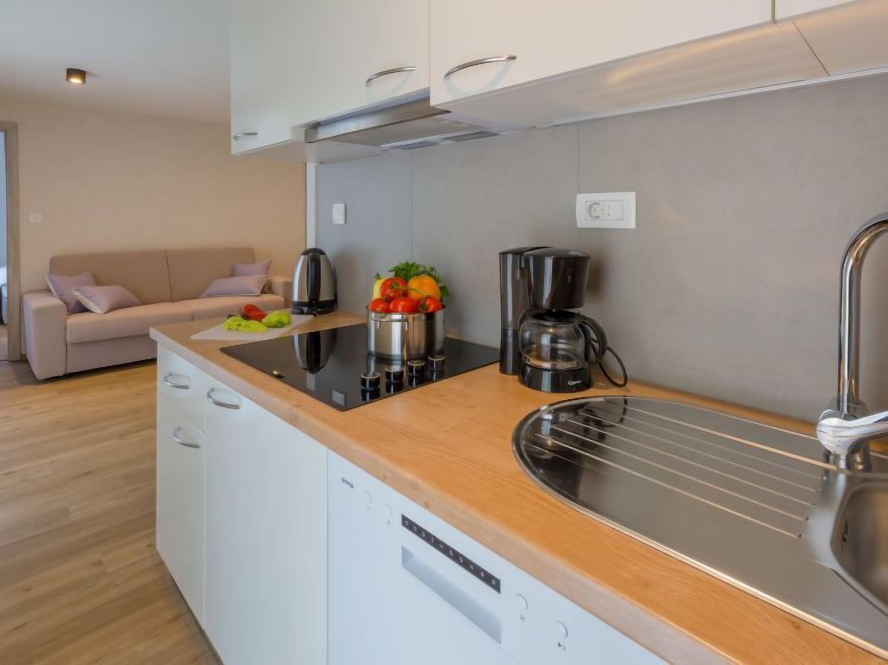 A modern kitchen with a built-in dishwasher, a coffee maker, and a fruit bowl on the counter.