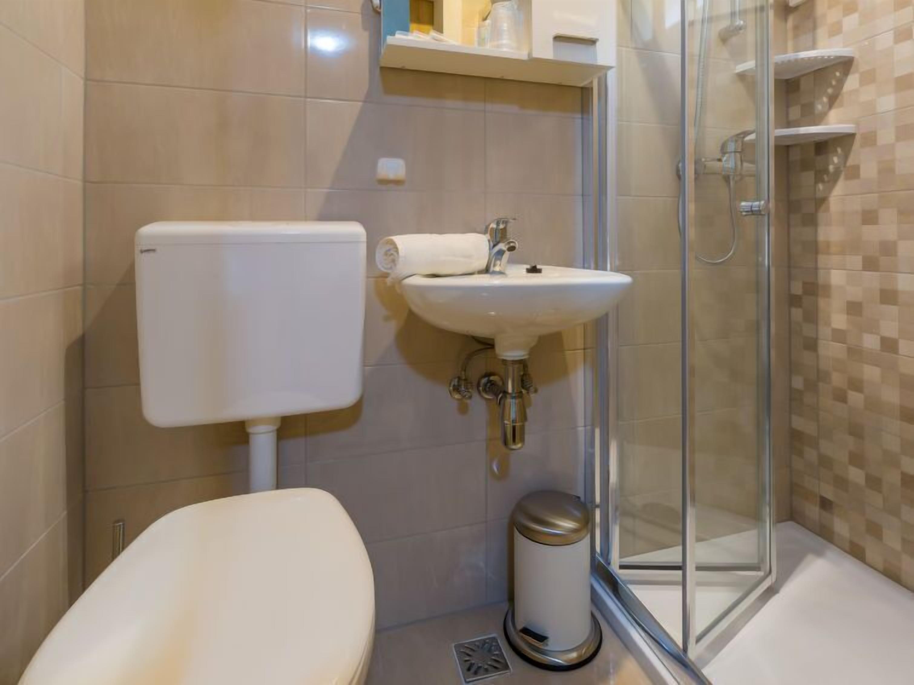Et moderne badeværelse med toilet, vask og glasbrusekabine.
