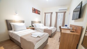 A hotel room with two beds, a desk, a chair, a TV, and an air conditioning unit. - 9Bodrum Butik Hotel (Bodrum)