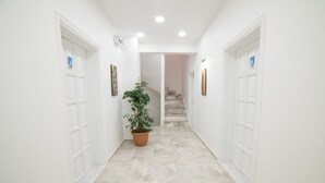 A hallway with white walls, a potted plant, and a staircase at the end. - 9Bodrum Butik Hotel (Bodrum)