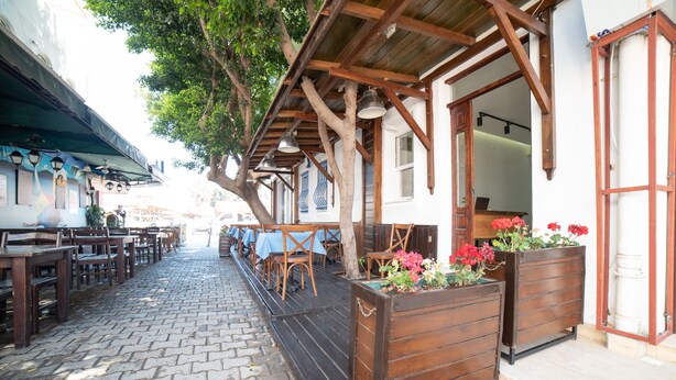 An outdoor café area with wooden tables and chairs, a brick pathway, and a wooden pergola structure. - 9Bodrum Butik Hotel (Bodrum)