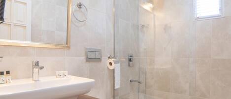 A modern bathroom with a glass-enclosed shower, a wooden vanity, and a large mirror.