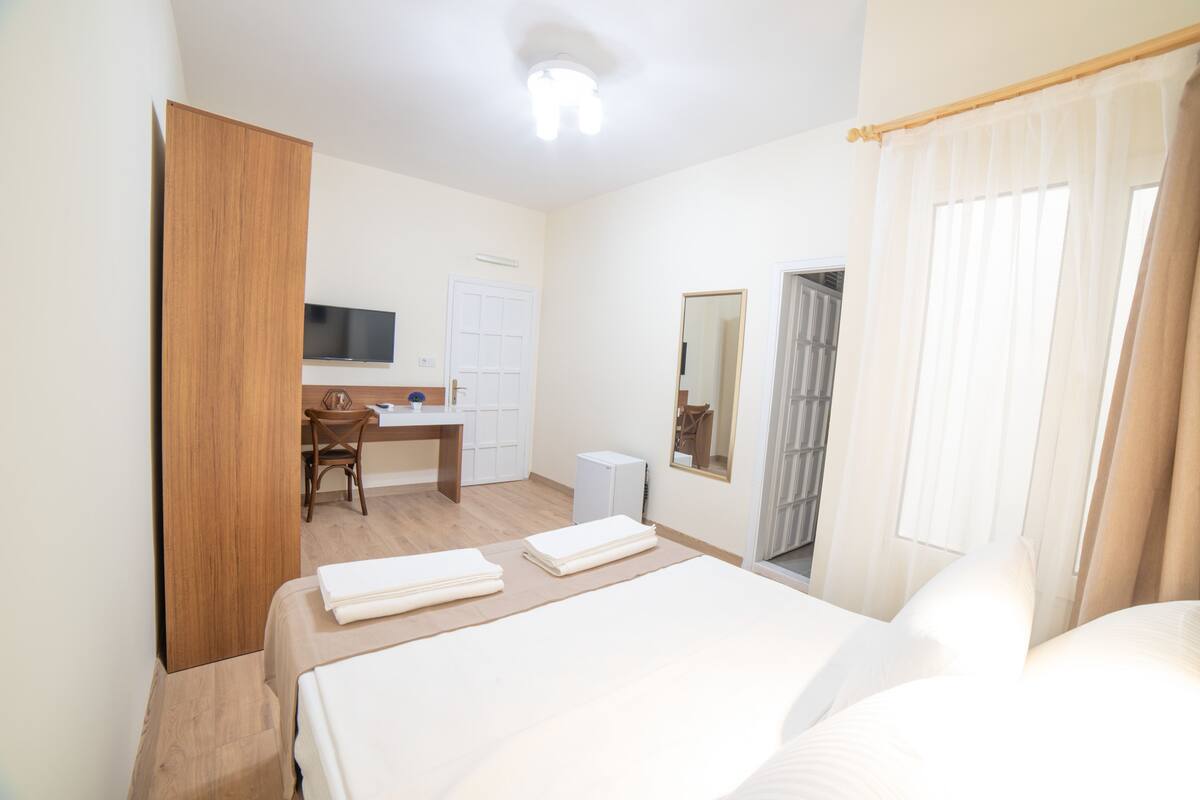 Una habitación de hotel con una cama, un escritorio, una silla, un televisor y un armario.