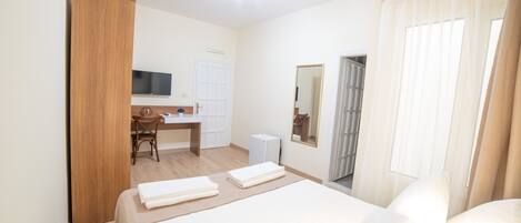 Una habitación de hotel con una cama, un escritorio, una silla, un televisor y un armario.