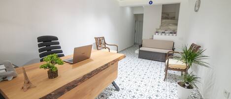 A modern office space with a wooden desk, a laptop, a potted plant, and a chair.