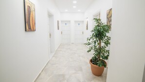 A hallway with white walls, a tiled floor, and a potted plant. There are doors at the end of the hallway. - 9Bodrum Butik Hotel (Bodrum)