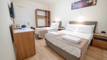 A hotel room with two beds, a wooden desk, a TV, and a painting on the wall.