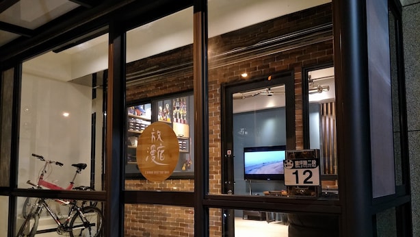 A hotel entrance with glass doors, a bicycle outside, and a sign indicating room number 12. - Letes stay (Shoufeng)