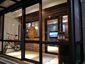 A hotel entrance with glass doors, a bicycle outside, and a sign indicating room number 12. - Letes stay (Shoufeng)