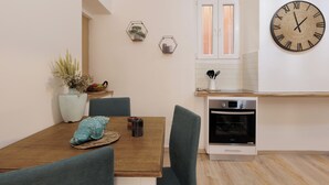 Une cuisine moderne avec une table à manger en bois, deux chaises, une horloge et une fenêtre.