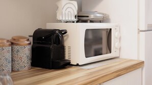 Une cuisine équipée d’un four à micro-ondes, d’une machine à café et de récipients décorés placés sur le plan de travail.