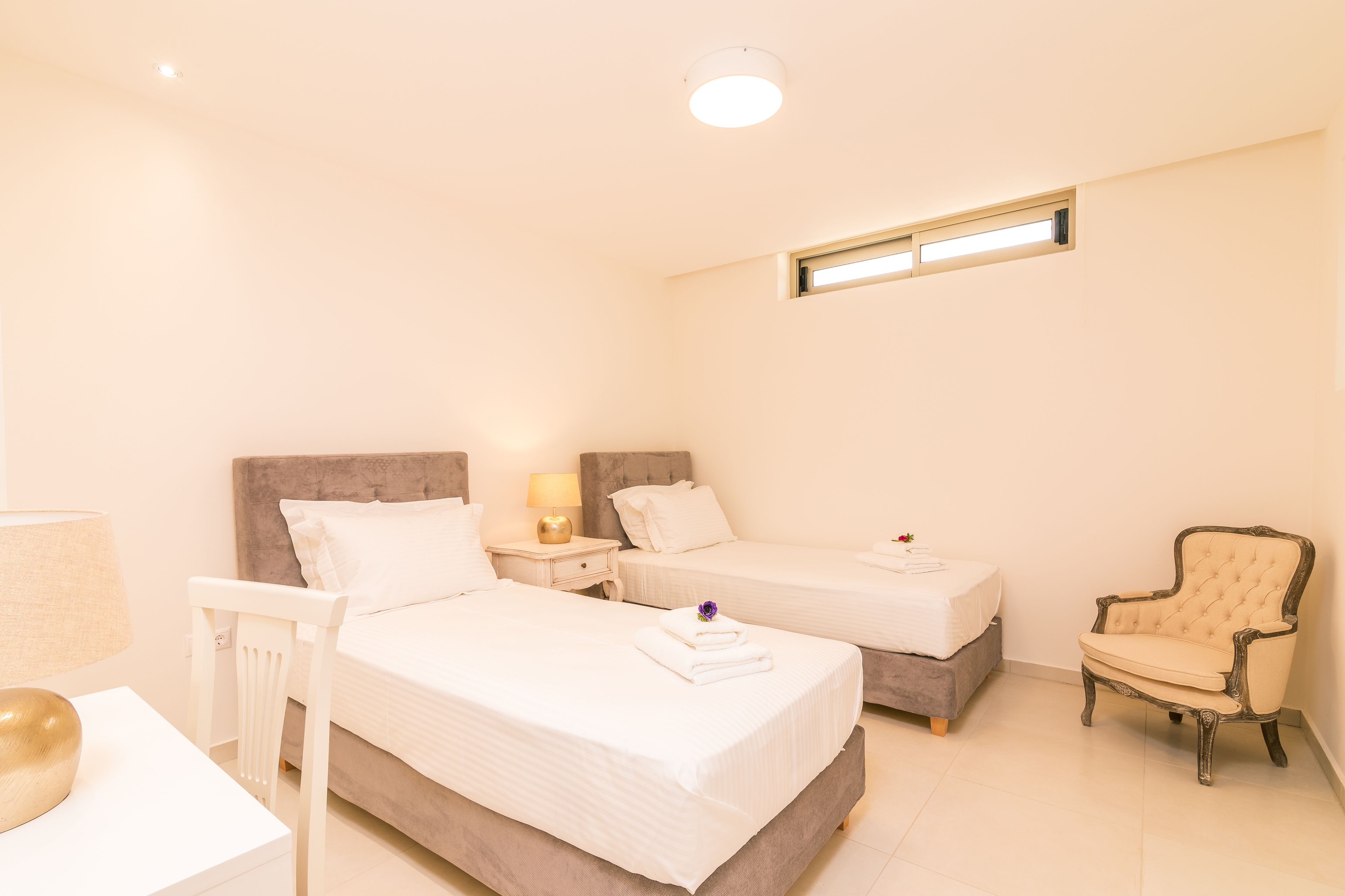 Camera d'albergo con due letti, una sedia, un comodino e una lampada.