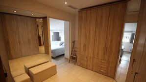 A bedroom with a large wardrobe, a bed, and a seating area with a ladder. - La Villa Jalna Chambres Appartement (Roquefort-les-Pins)