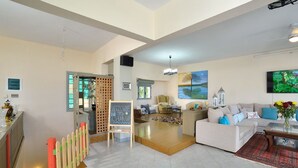 A spacious living area with a sofa set, a coffee table, and a TV mounted on the wall.