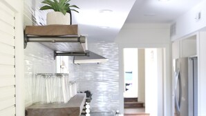 A modern kitchen with a marble countertop, built-in shelves, and a stainless steel refrigerator.