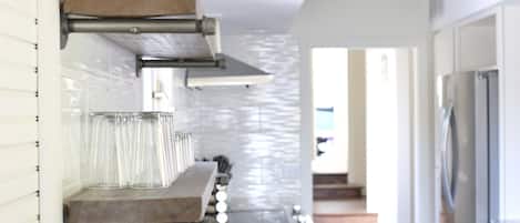 Una cocina moderna con encimera de mármol, estanterías empotradas y un refrigerador de acero inoxidable.