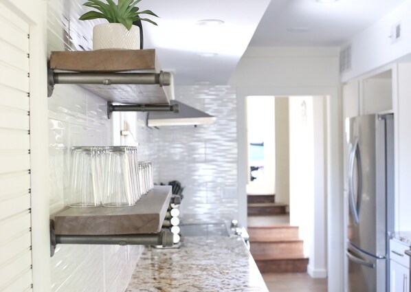 A modern kitchen with a marble countertop, built-in shelves, and a stainless steel refrigerator. - Life Is Always Better At Lake Life Charlevoix - Golf Cart Included! (Charlevoix)