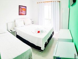 Una habitación de hotel con cama, mesita de noche, escritorio y pared verde.