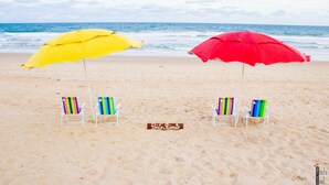 A beach with two colorful umbrellas and beach chairs. - Pousada Porto Riomar (Ipojuca)