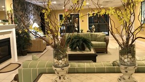 A lobby with a green sofa, a fireplace, and decorative plants in glass vases. - Beachfront 1Br/1Ba condo, free parking & WiFi  w/ Heated Pool (North Wildwood)