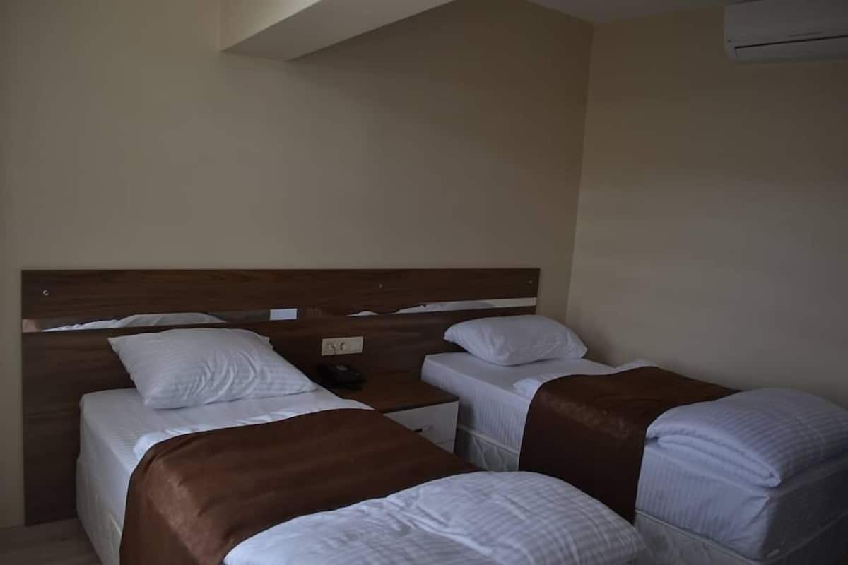 A hotel room with two single beds, a wooden headboard, a nightstand, and a small table.