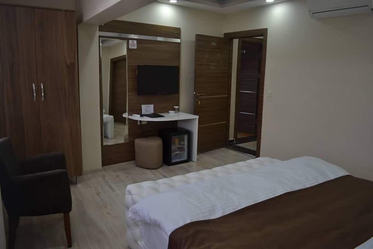 A bedroom with a bed, a desk, a chair, and a wardrobe.