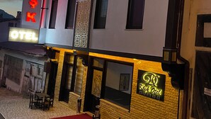 Un hotel con un letrero llamativo que dice “KÖSKÖK HOTEL” y un letrero más pequeño que indica “Kirk Ötel”. El edificio presenta un diseño moderno con una combinación de texturas de piedra y yeso.