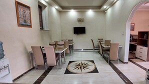 Un comedor con varias mesas y sillas, un dispensador de agua, un televisor de pantalla plana montado en la pared y un diseño decorativo en el suelo.