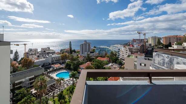 Un paisaje urbano costero con cielo despejado, una piscina y varios edificios.