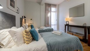 Una habitación de hotel con dos camas, un espejo grande, un escritorio y una ventana con cortinas.
