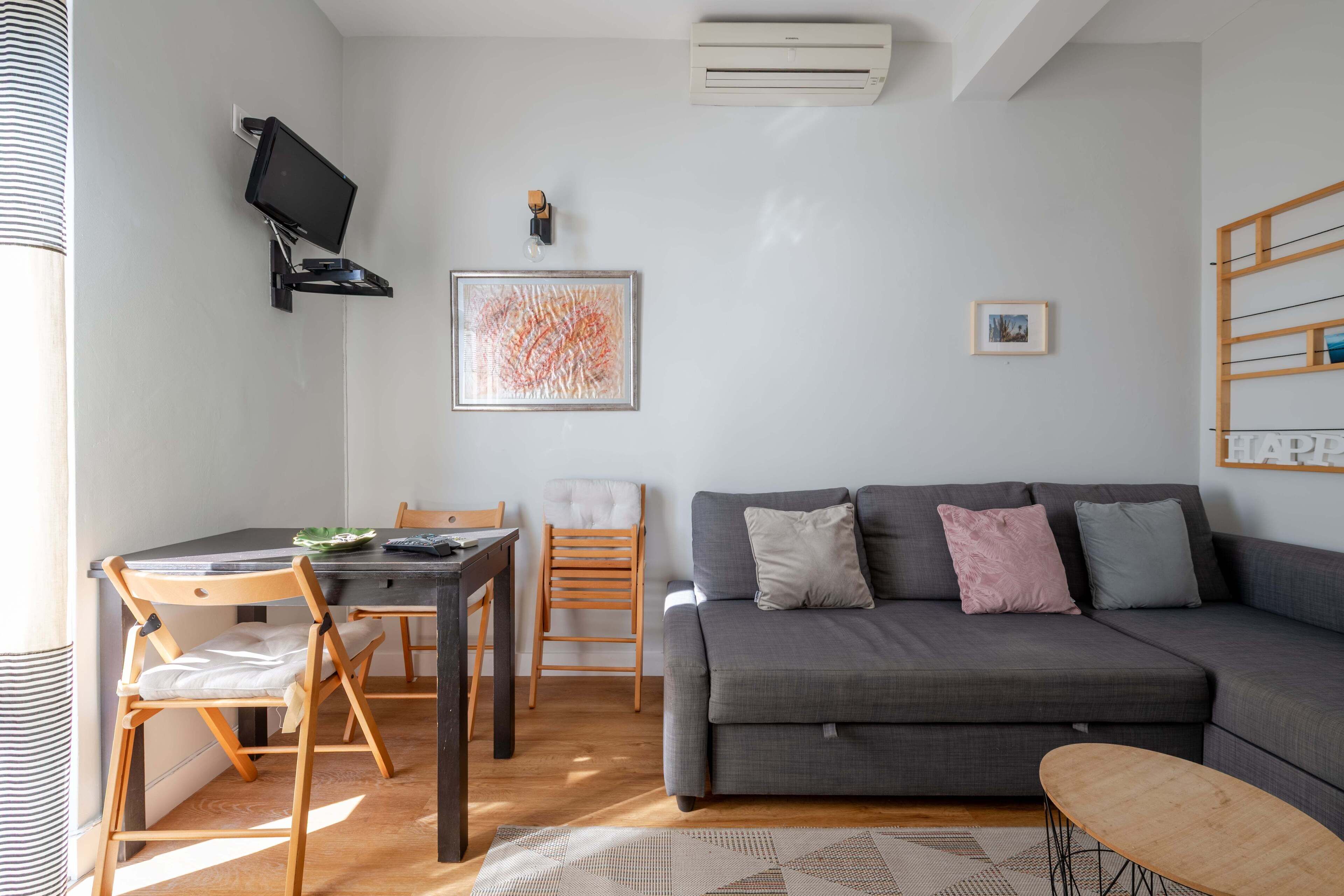 Un salon moderne avec un canapé gris, une table à manger en bois et des chaises.
