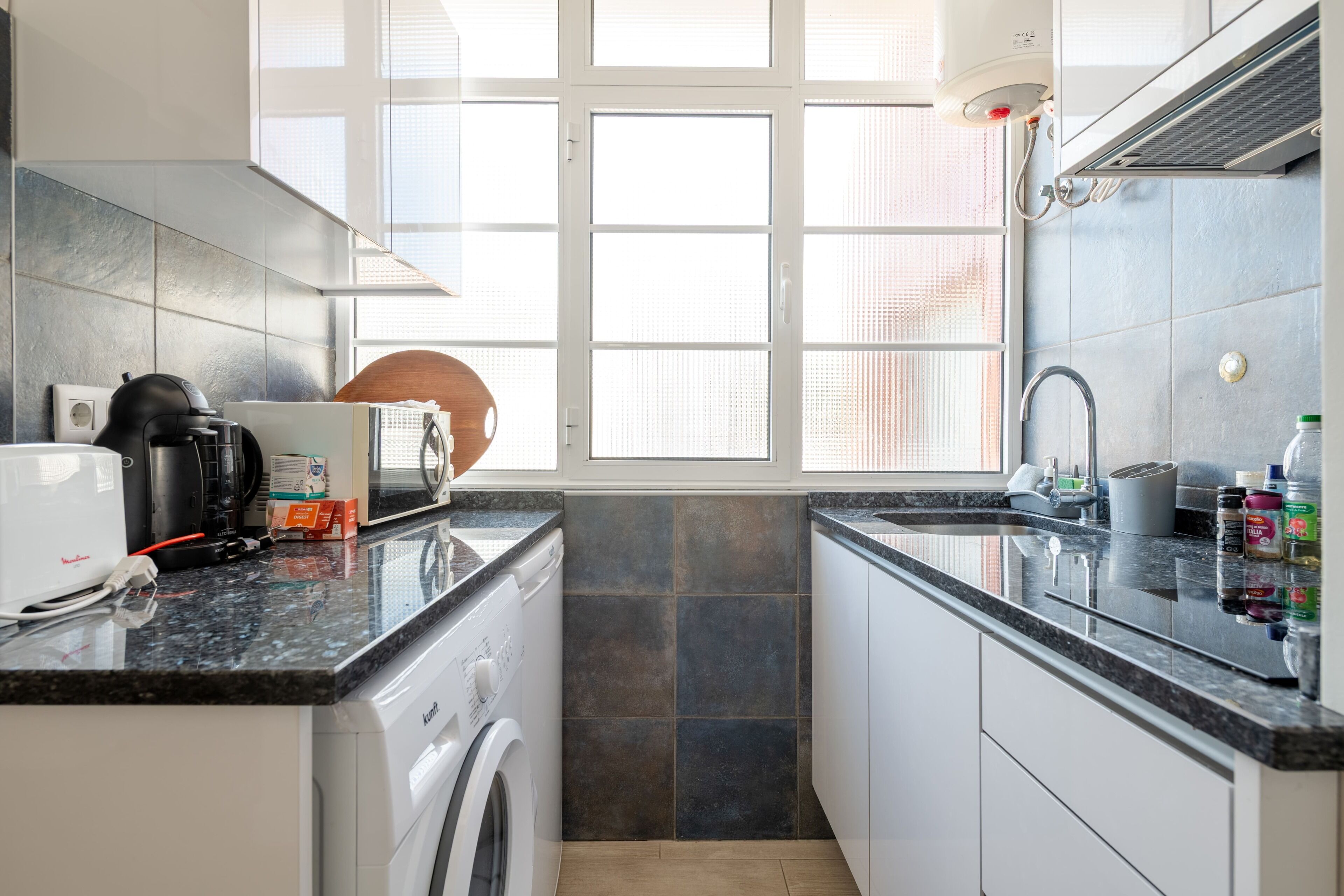 A compact kitchen with a washing machine, a microwave, and a sink.