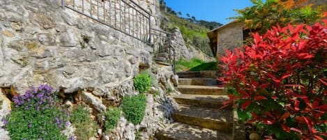 Una escalera de piedra con peldaños que suben hacia un edificio con barandilla de metal.