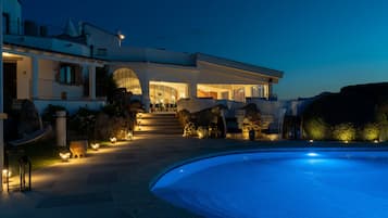 A modern villa with a swimming pool, outdoor lighting, and a well-maintained garden.
