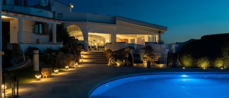 A modern villa with a swimming pool, outdoor lighting, and a well-maintained garden.