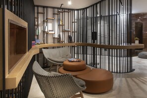 Um interior moderno com uma escrivaninha de madeira curva, duas cadeiras estampadas e um banquinho redondo.