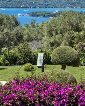 A landscaped garden with neatly trimmed bushes, a spherical topiary, and vibrant purple flowers in the foreground. - Sulia House Porto Rotondo, Curio Collection by Hilton (Olbia)