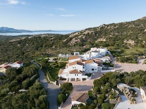 A coastal villa complex with multiple buildings, a winding driveway, and a view of the sea and hills. - Sulia House Porto Rotondo, Curio Collection by Hilton (Olbia)
