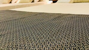 Una habitación de hotel con dos camas, un tapete estampado y lámparas fijadas a la pared.
