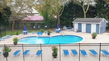A swimming pool with lounge chairs and a shed in a fenced backyard.