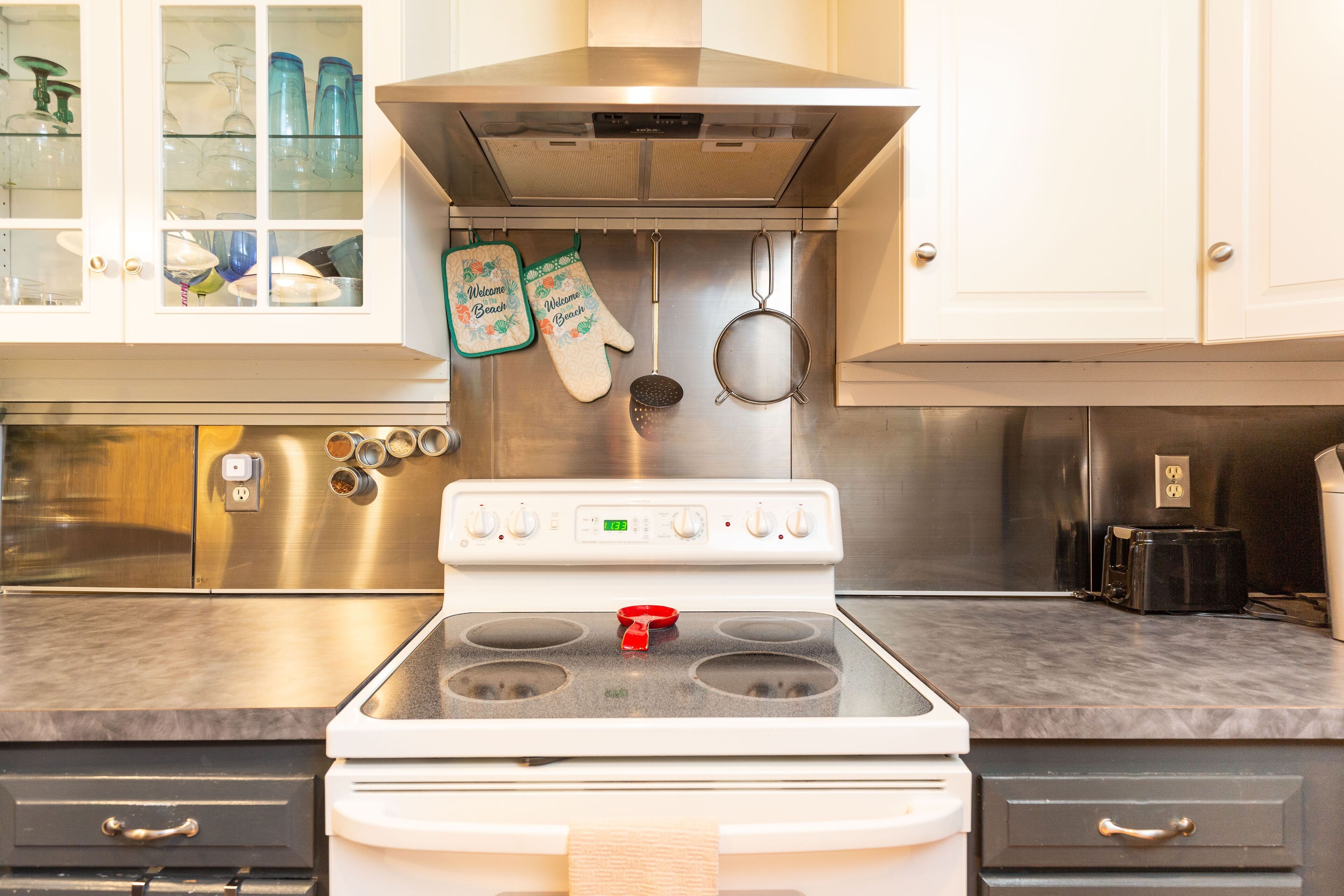 Una cocina con estufa blanca, armarios de acero inoxidable y encimera de mármol.